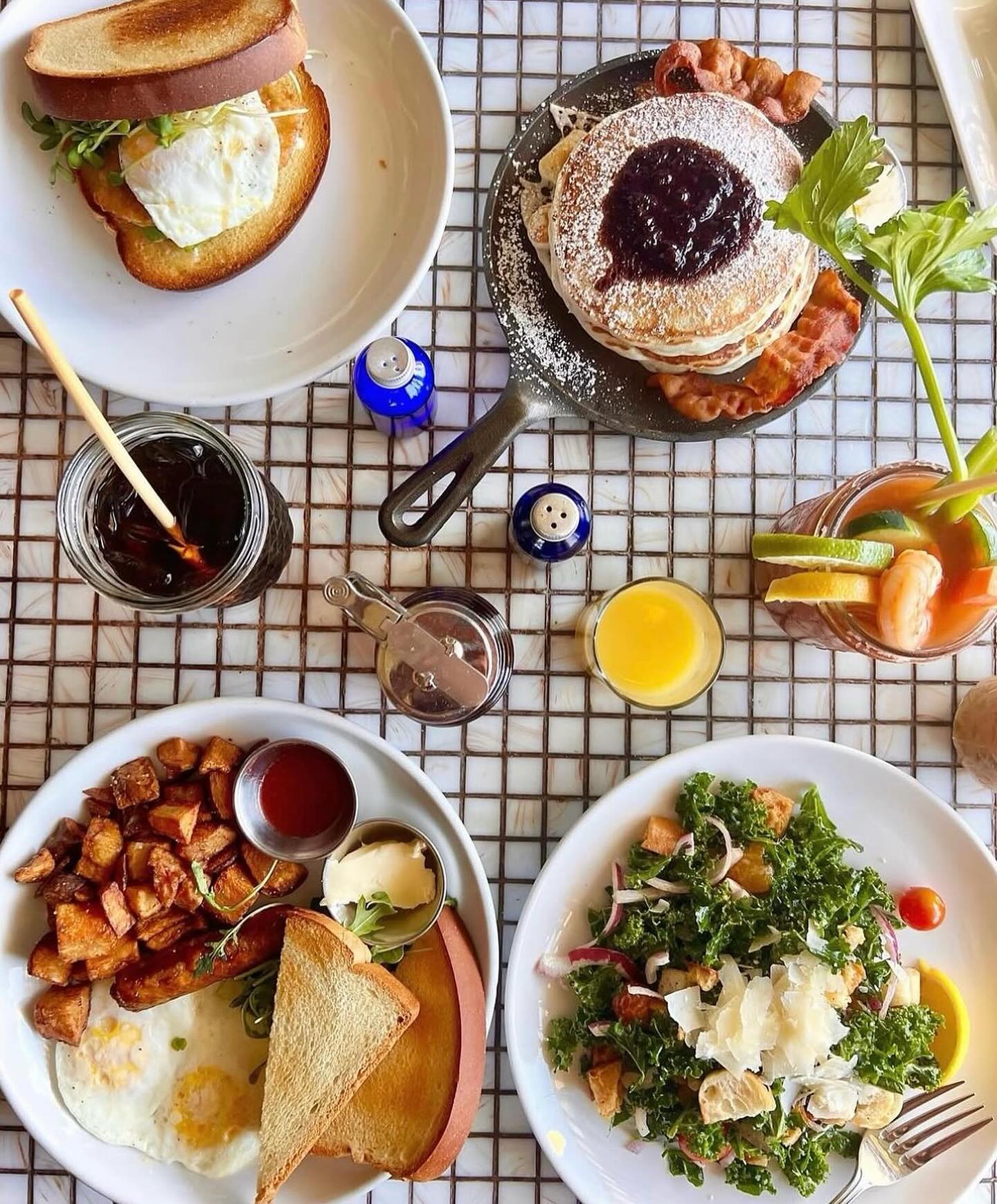 Full table of breakfast and brunch plates, including pancakes, eggs, and salad.