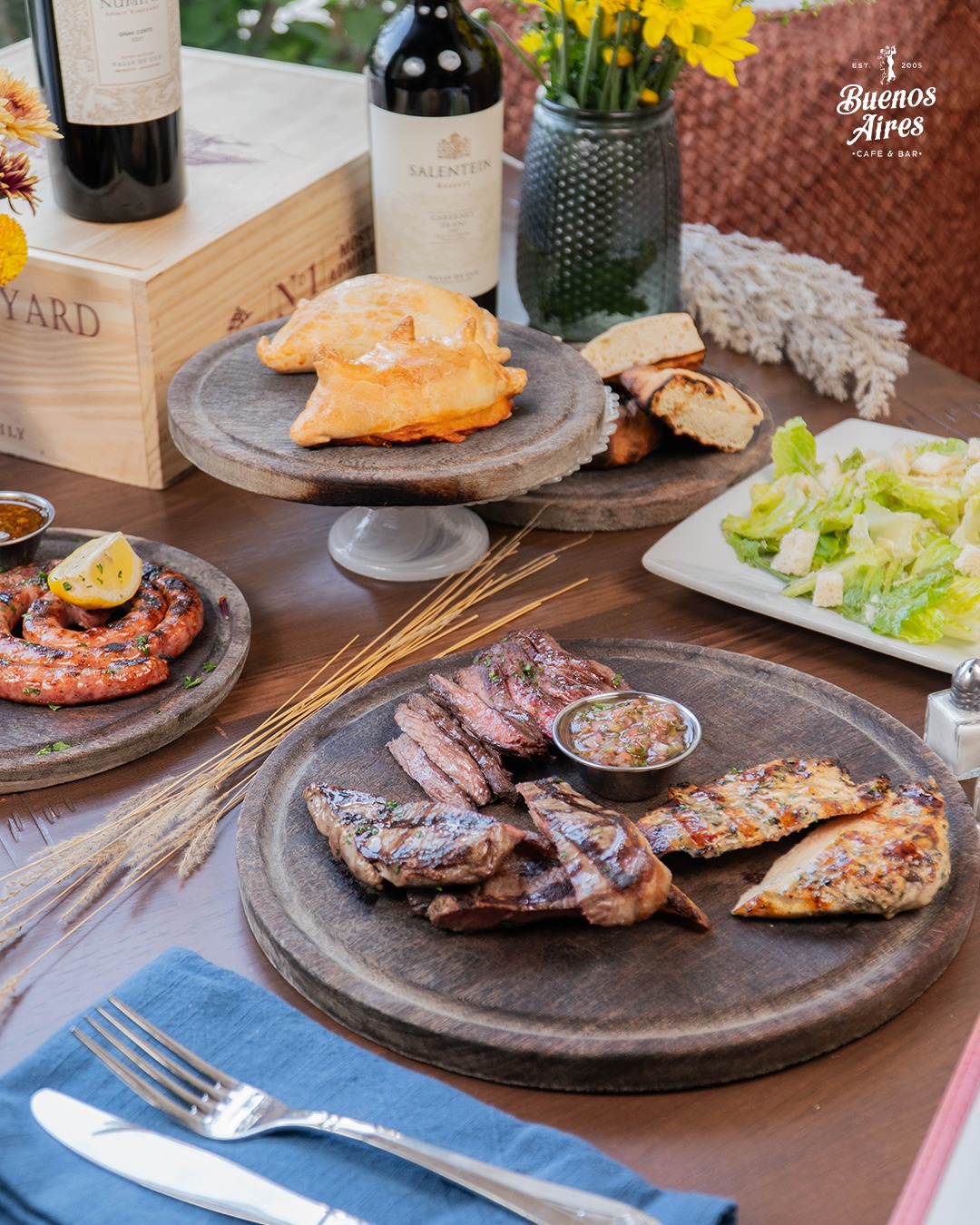 Argentinian meal with grilled meats, empanadas, and red wine.