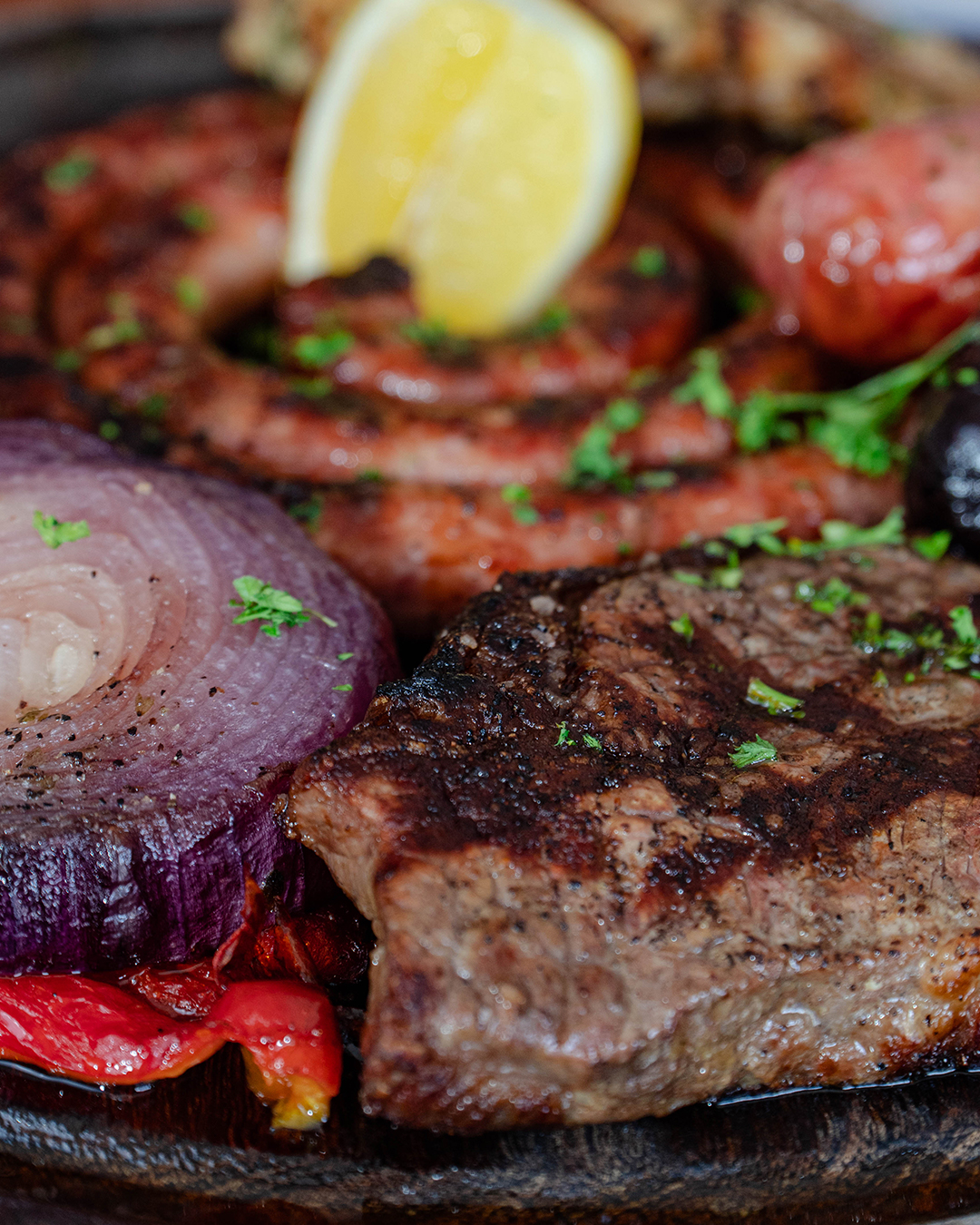 Grilled steak, coiled sausages, red onion, lemon, and roasted peppers.