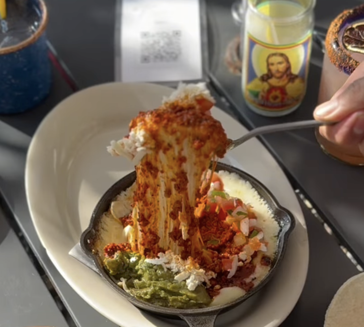 Fork pulls stringy melted cheese and chorizo from a skillet.