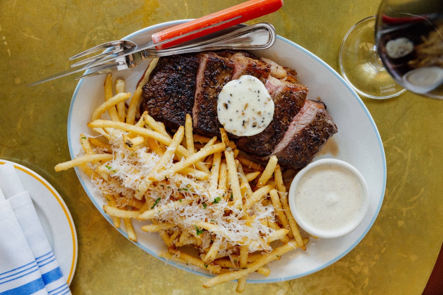 Sliced steak, french fries with grated cheese, butter, and sauce.