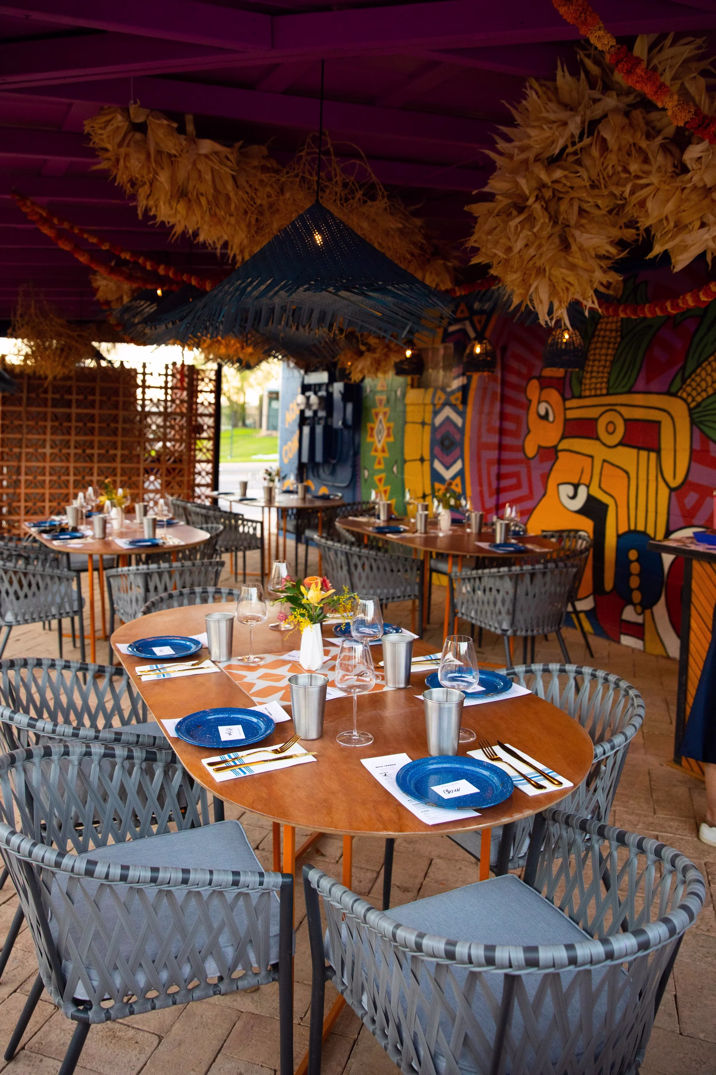 Colorful outdoor restaurant with tables, chairs, and vibrant wall murals.