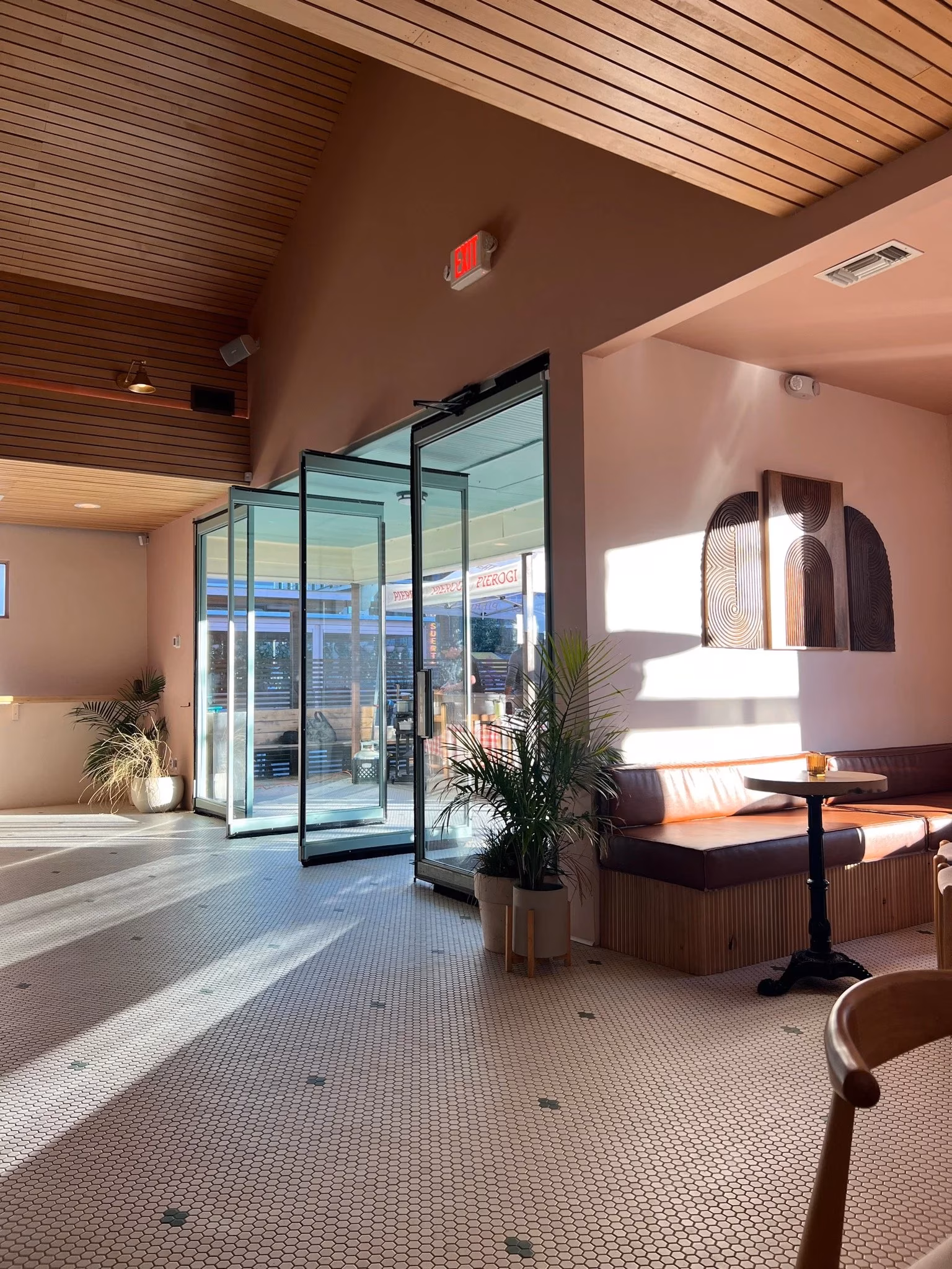 Cafe interior with hexagonal tile floor, glass doors, and sunlit booths.