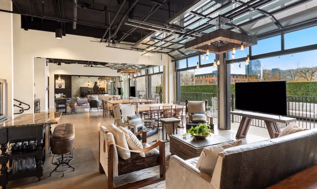 Industrial-style open lounge with dining area and large glass doors.