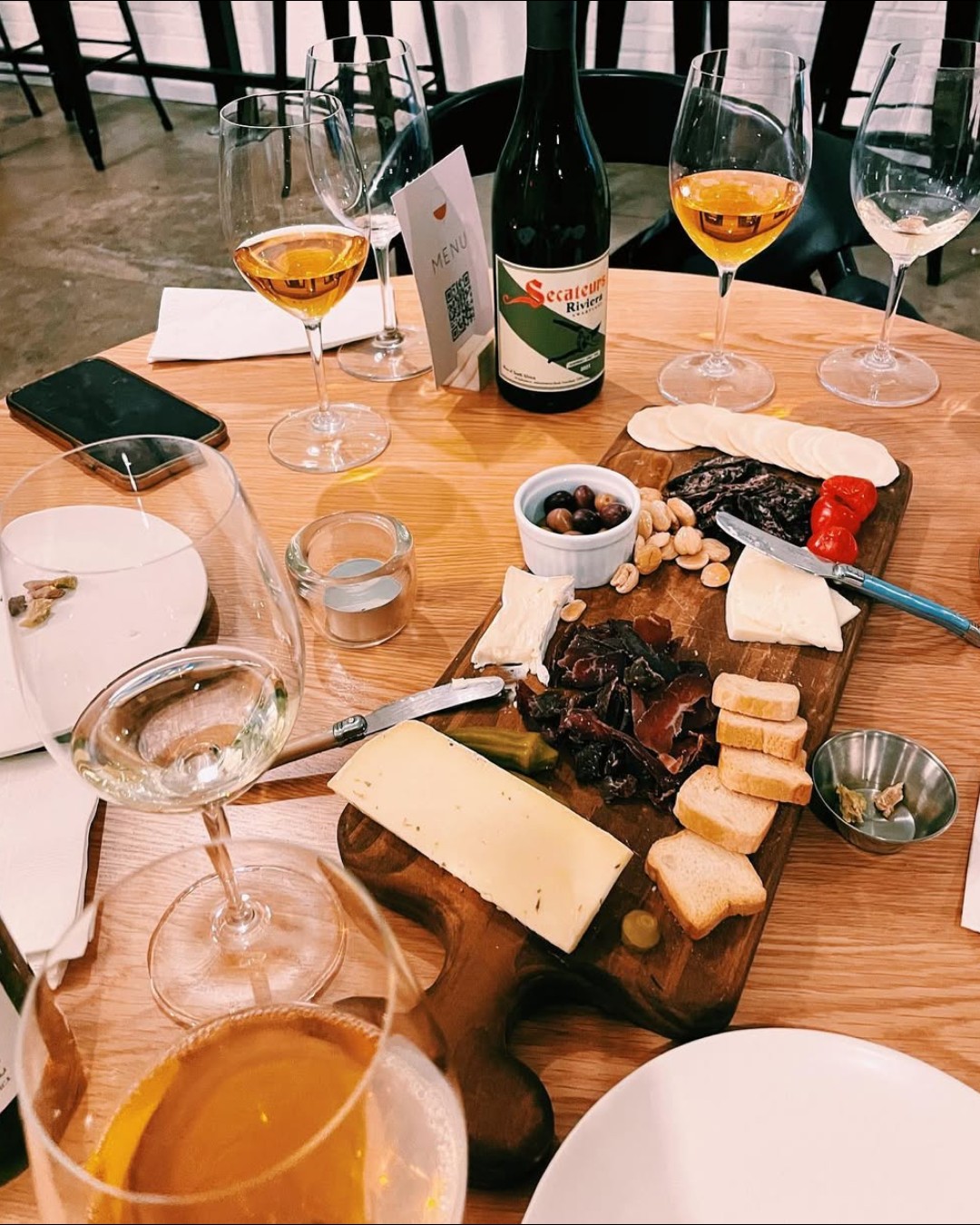 Multiple wine glasses, a bottle, and a cheese and charcuterie board.