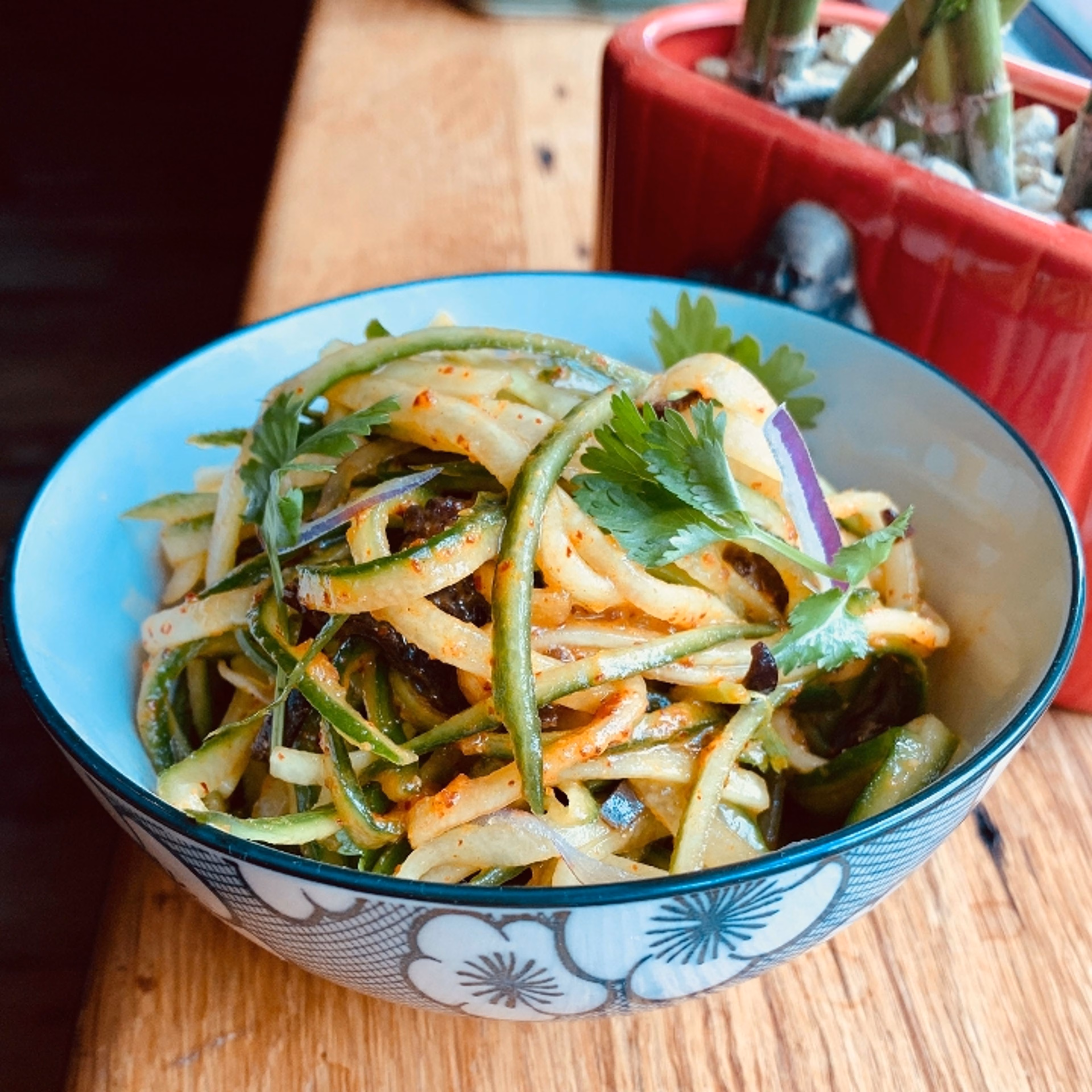 Shredded cucumber, red onion, and cilantro salad in a patterned bowl.