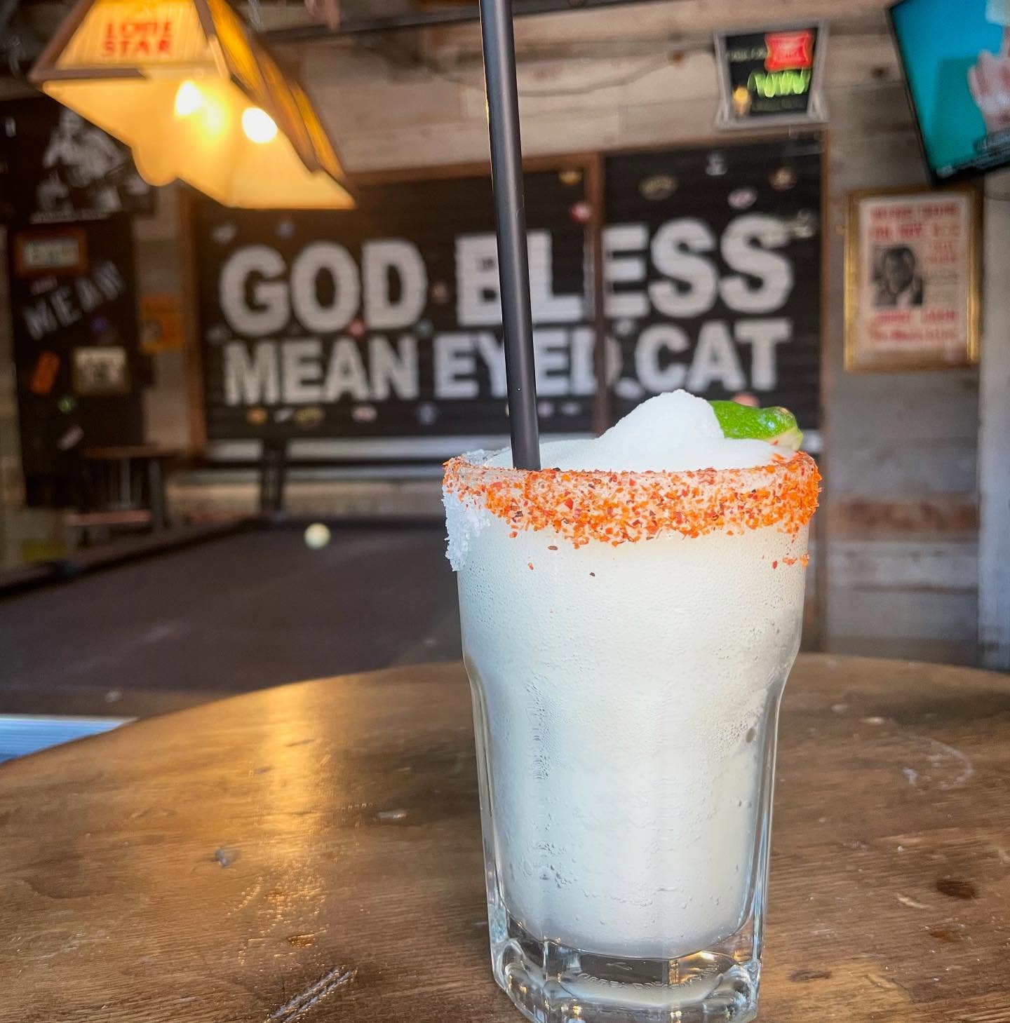 White frozen drink with a spiced rim, lime, and black straw.