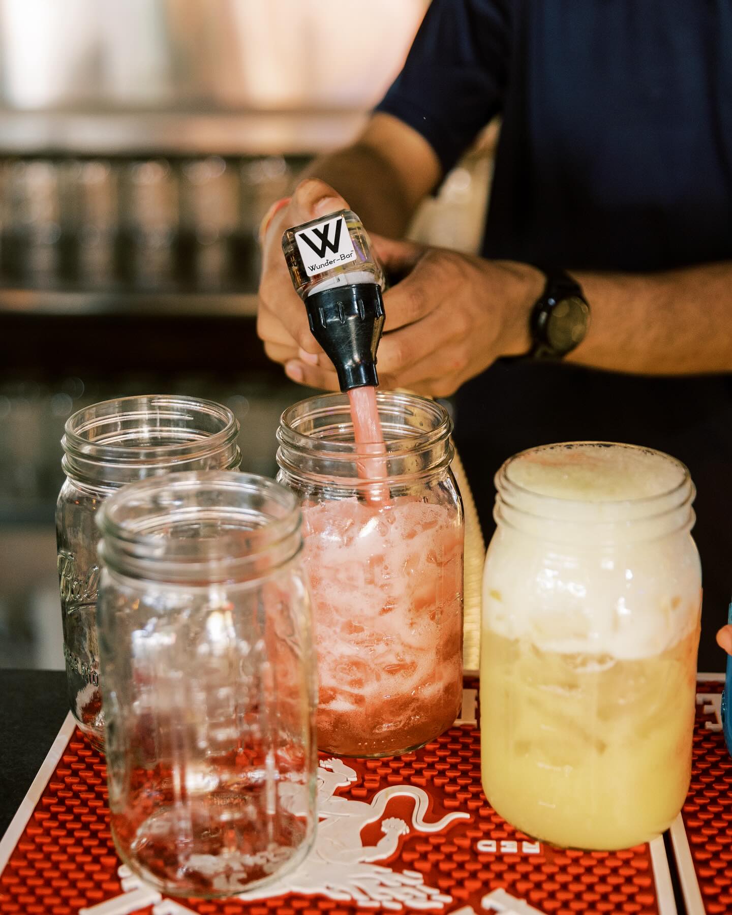 Bartender fills mason jar with pink drink using Wunder-Bar pourer.
