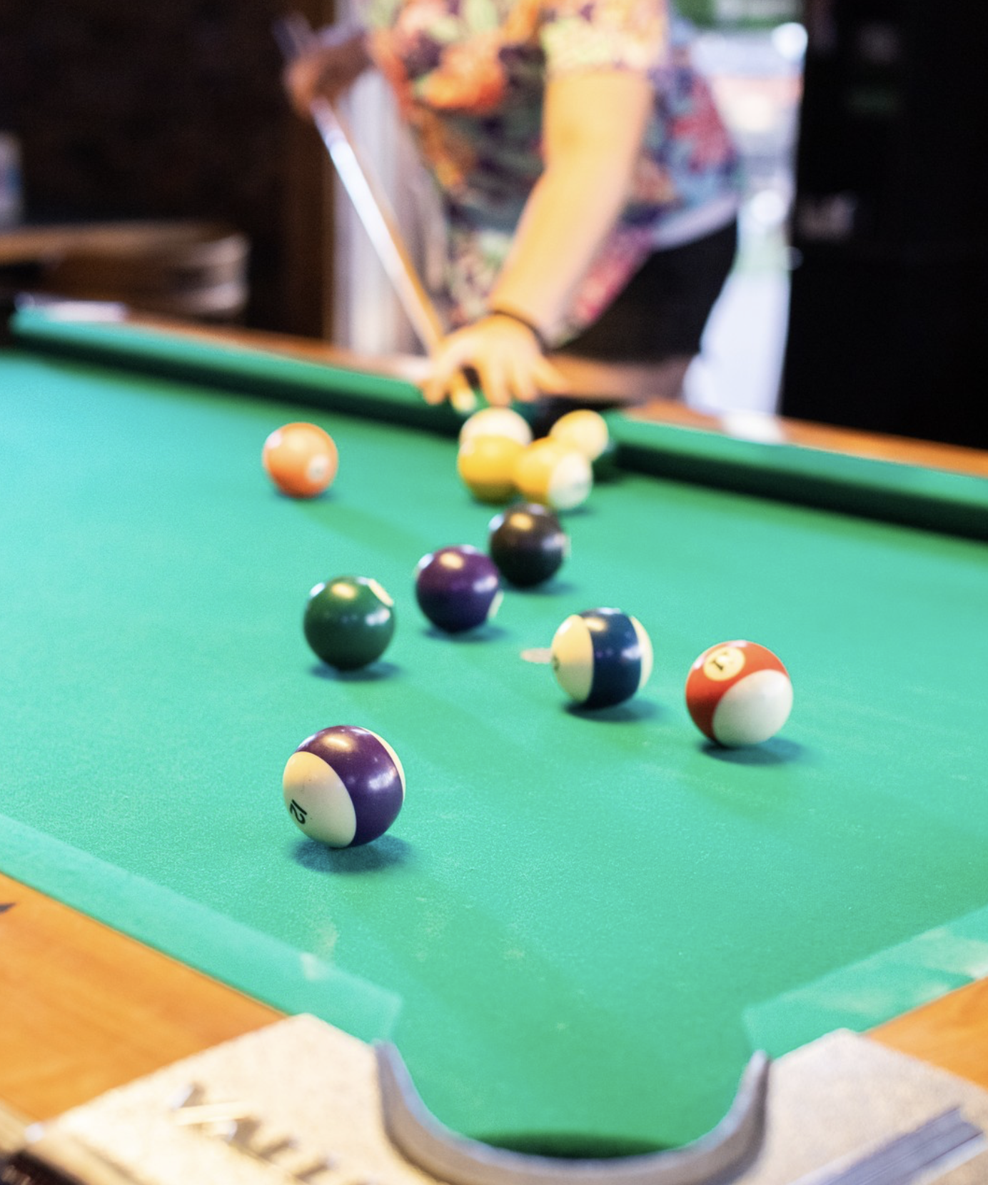 Player prepares to strike pool balls on a green felt table.
