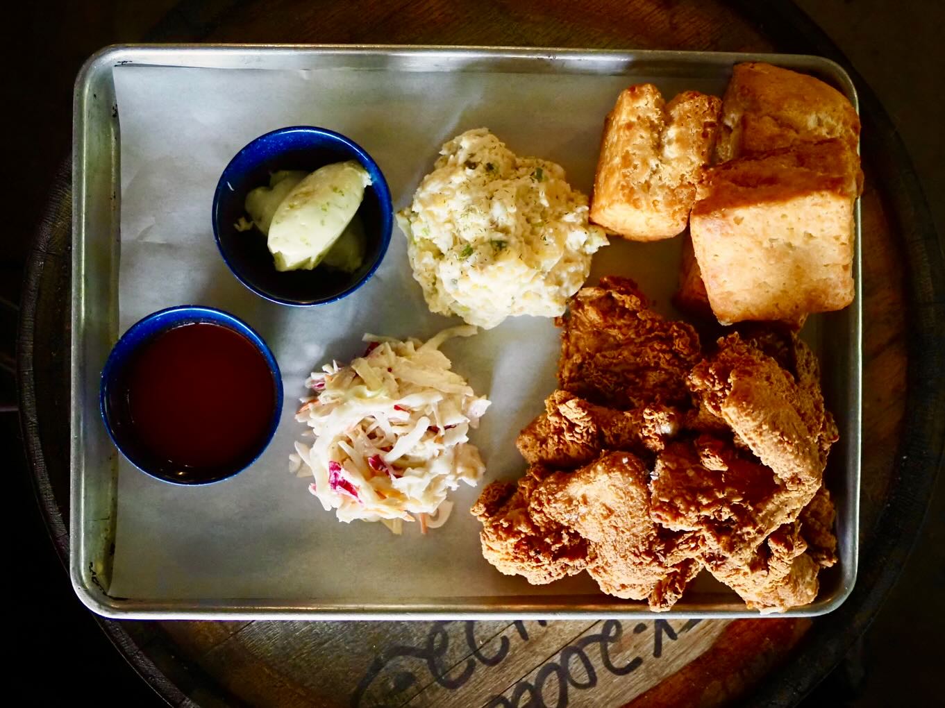 Fried chicken, biscuits, potato salad, coleslaw, butter, and red sauce.