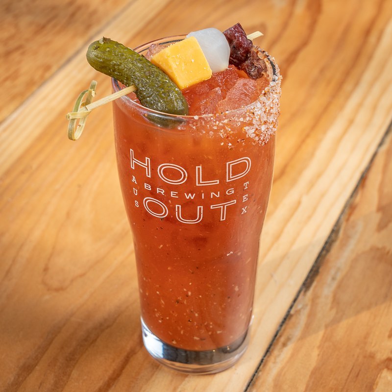 Bloody Mary cocktail with pickle, cheese, onion, and meat garnish.