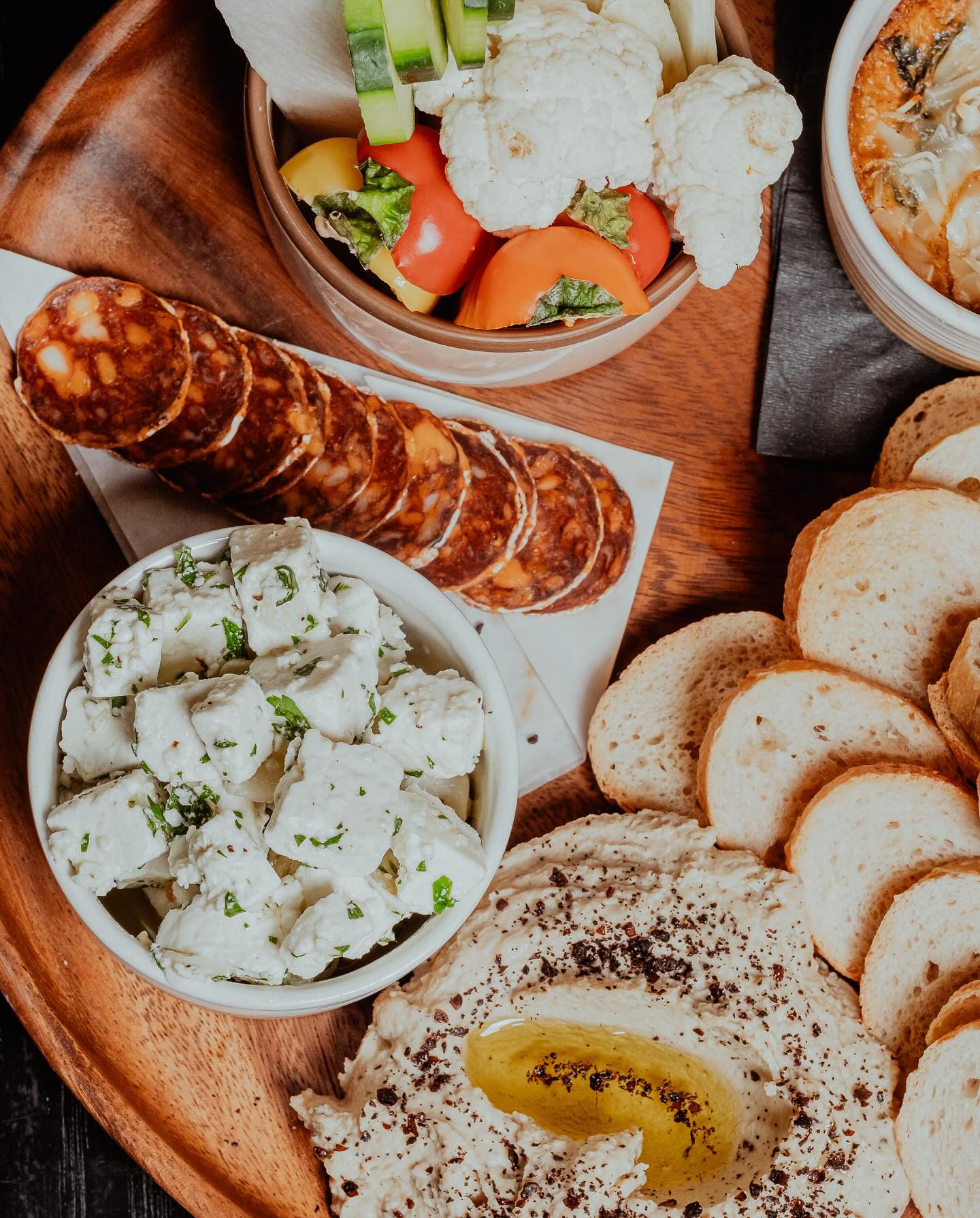 A selection of charcuterie, cheese, hummus, vegetables, and bread.