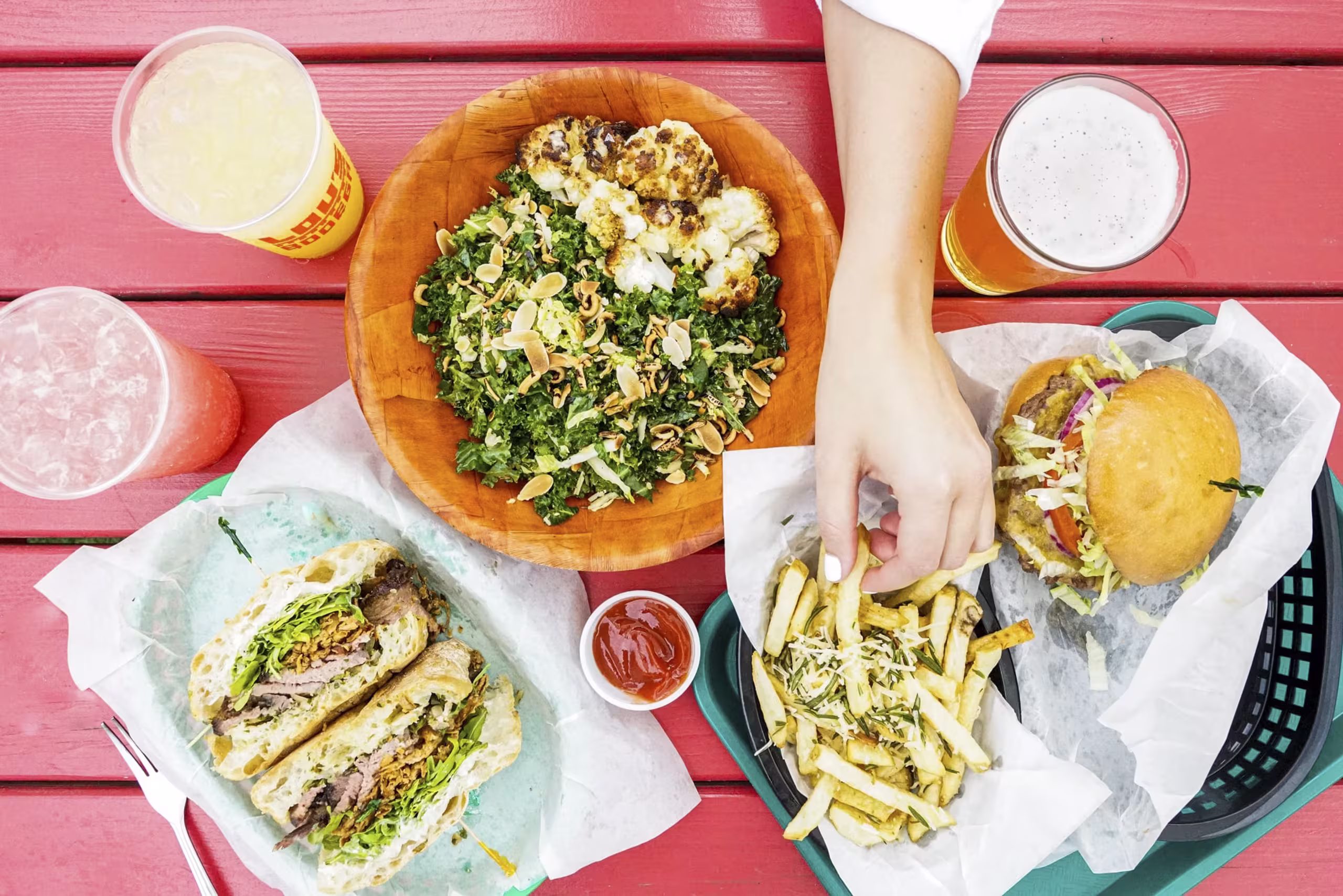 Overhead view of a hand picking fries from a varied meal.