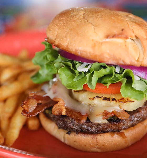 Cheeseburger with bacon, grilled pineapple, lettuce, tomato, onion, and fries.