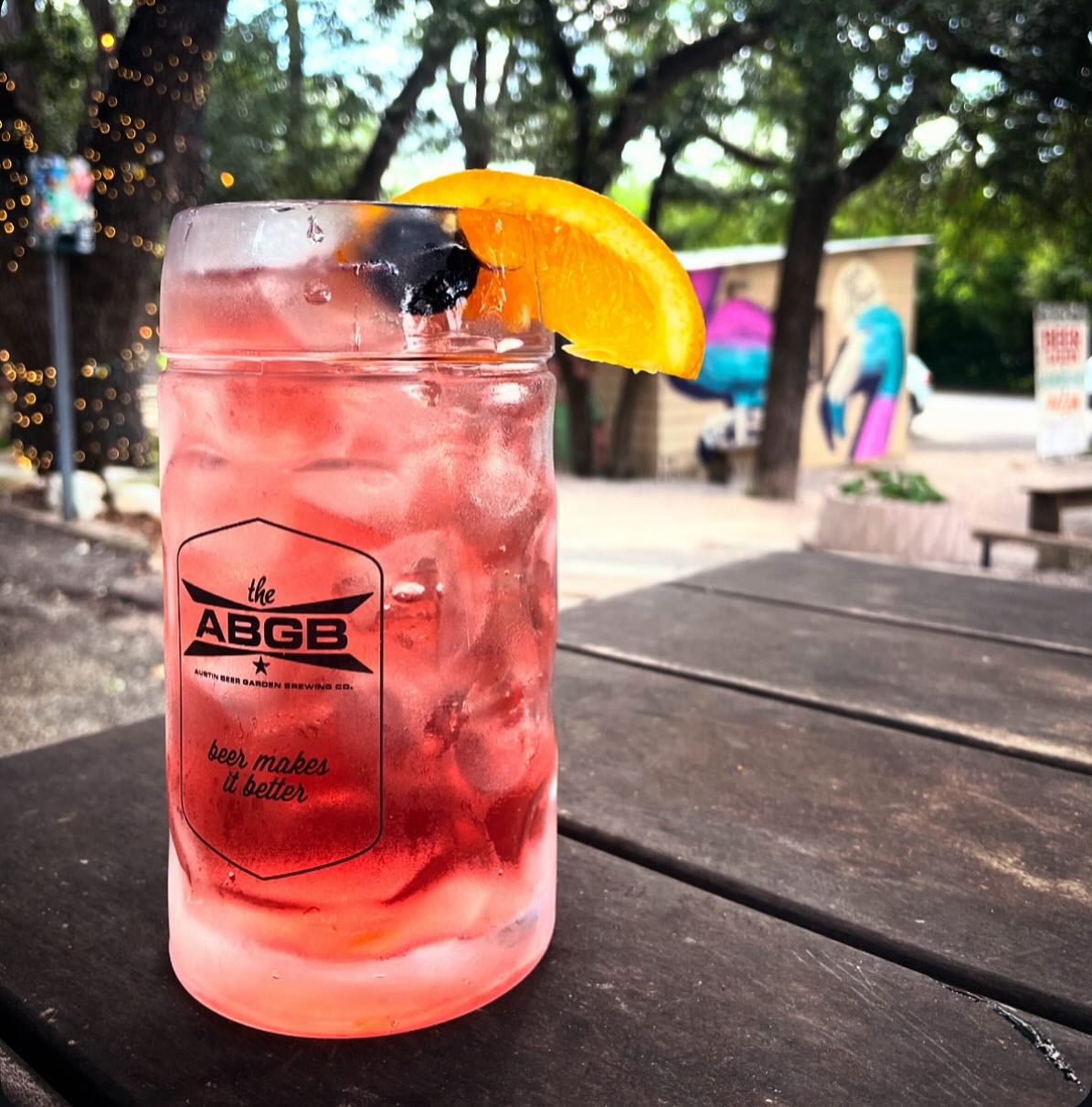 Red iced drink with ABGB logo, orange slice, and berry.