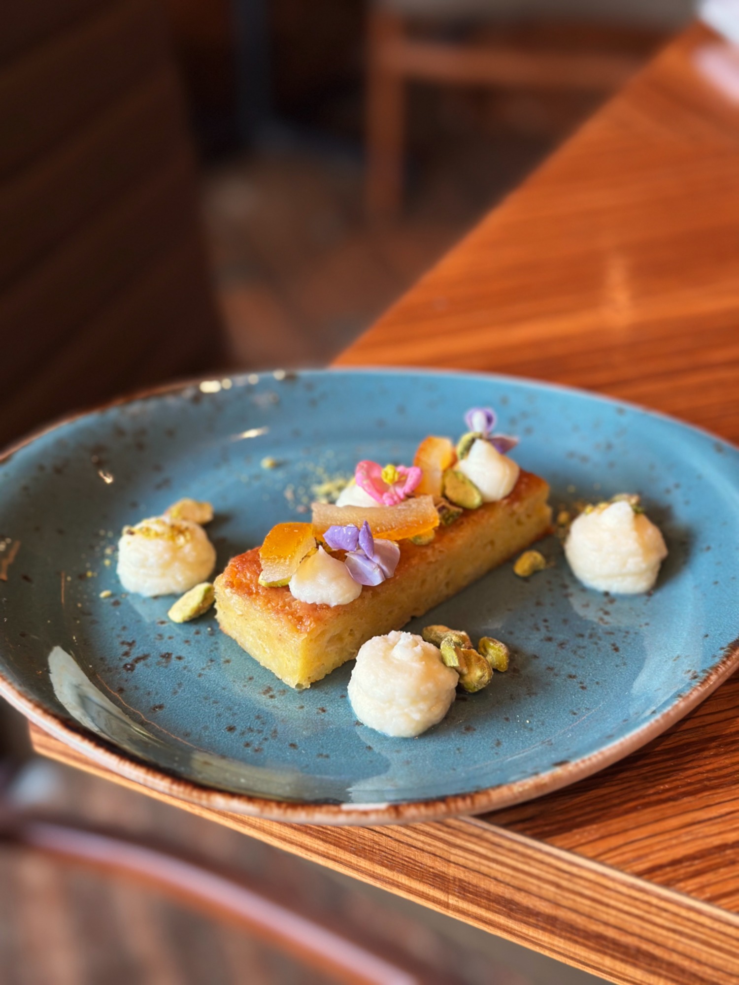 Rectangular dessert bar with candied fruit, flowers, and cream on blue plate.