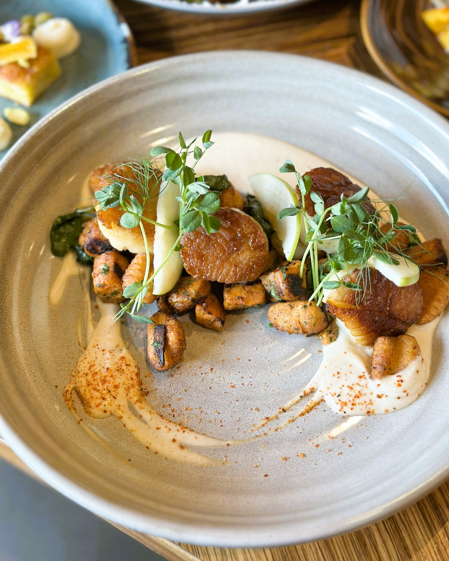 Golden seared rounds with roasted chunks, apple, sprouts, and creamy sauce.