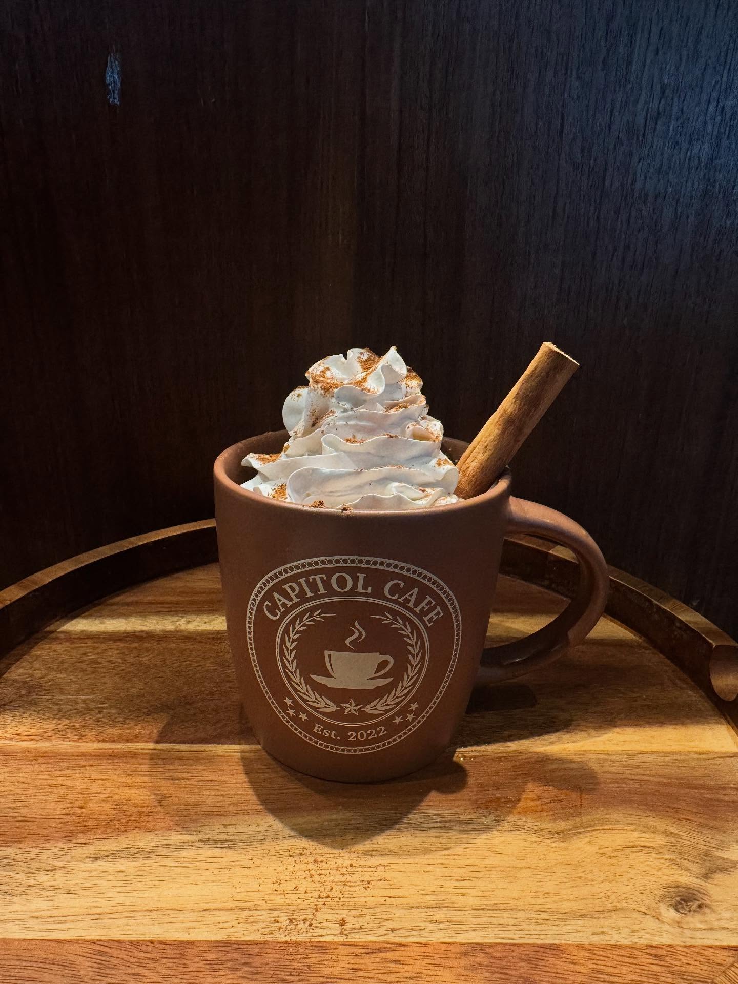 Capitol Cafe mug with whipped cream, cinnamon dusting, and cinnamon stick.