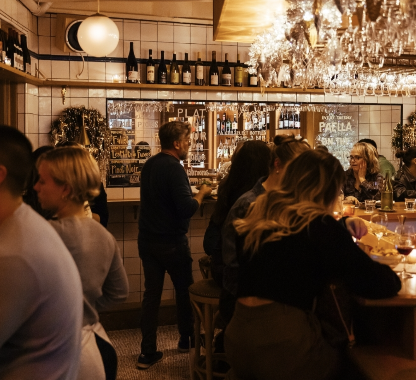 People gathered at a dimly lit bar with bottles and glassware.