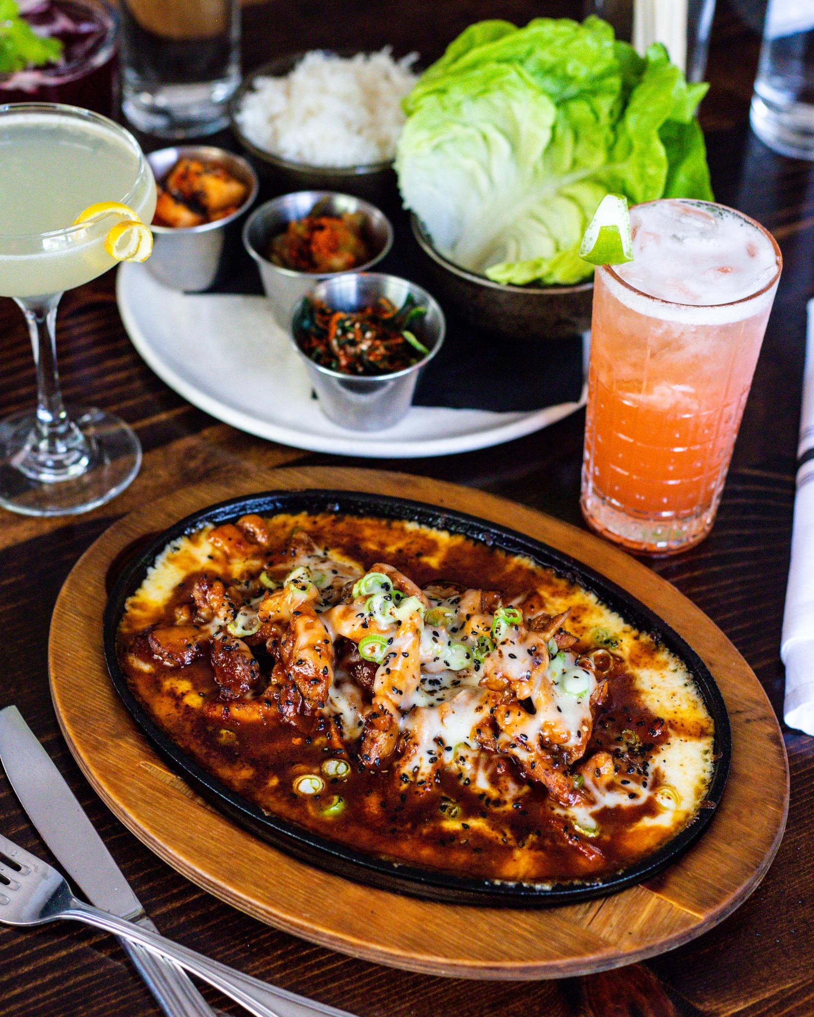 Sizzling Korean chicken and cheese, banchan, rice, lettuce, and cocktails.