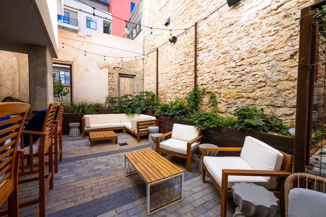 Outdoor patio with stone walls, wooden furniture, and string lights.