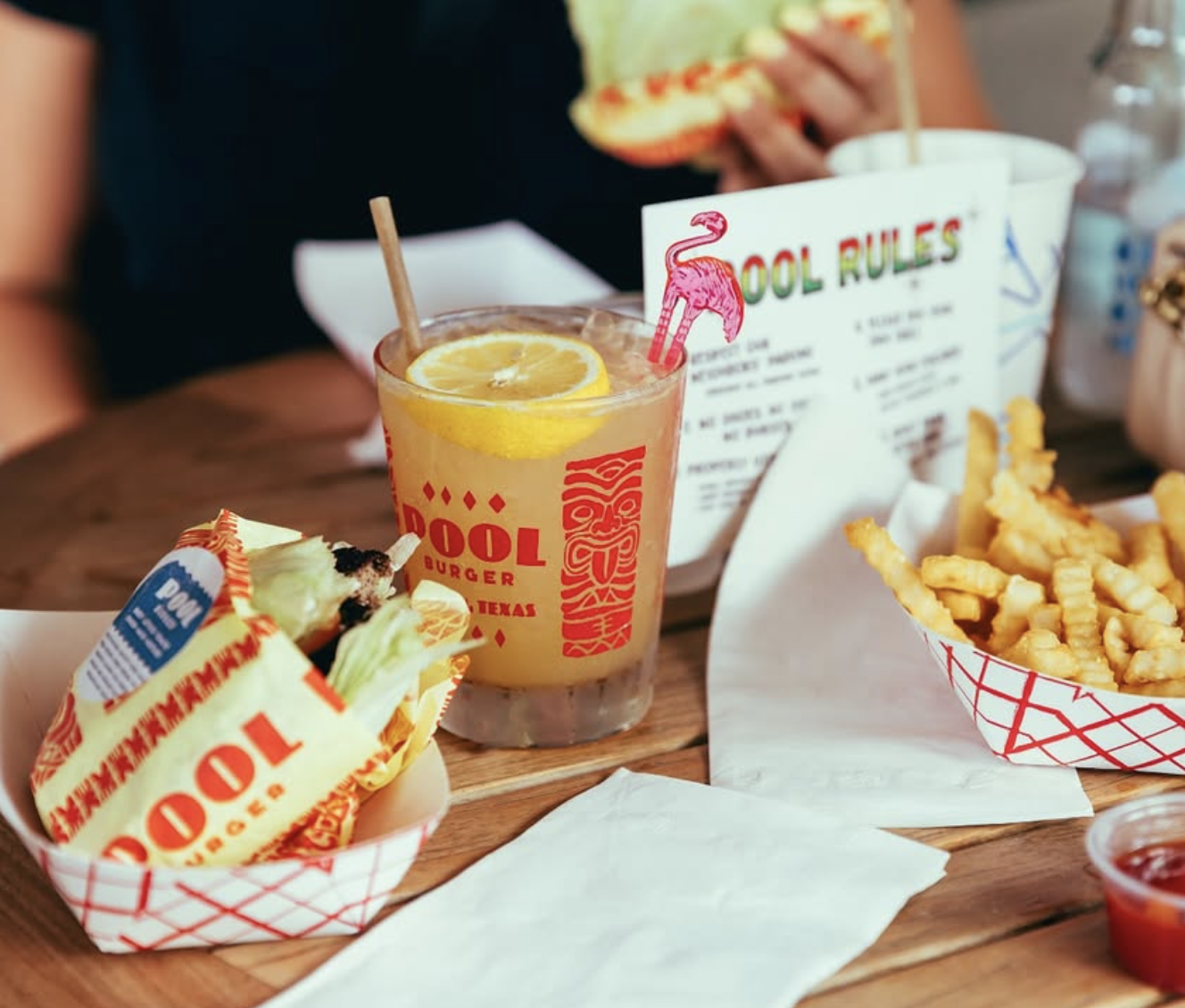 Burger, fries, and a lemon drink on a table at Pool Burger.
