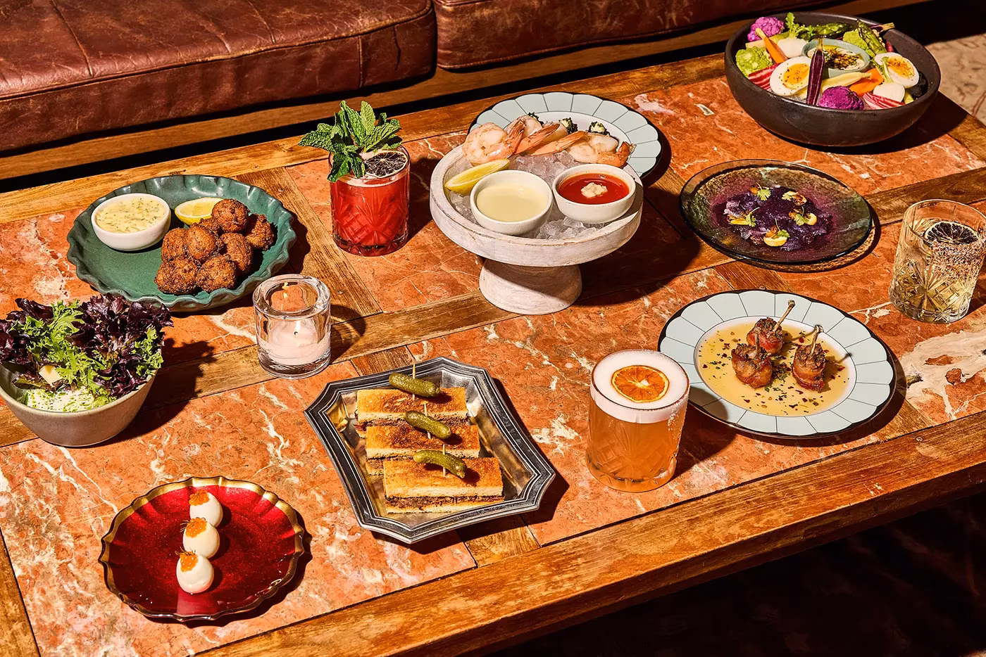 A table full of diverse appetizers and cocktails on a marble surface.