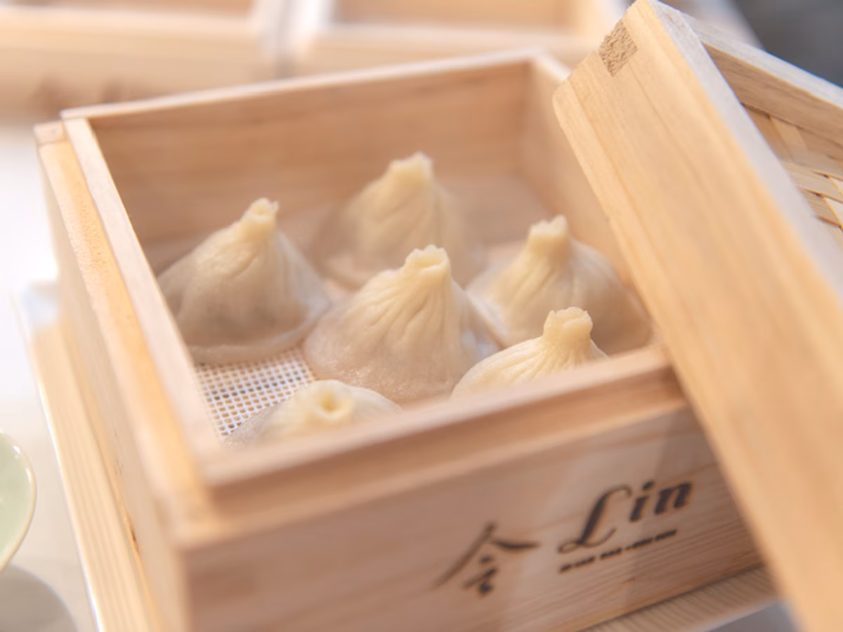 Steaming dumplings in a wooden steamer, lid partially open.