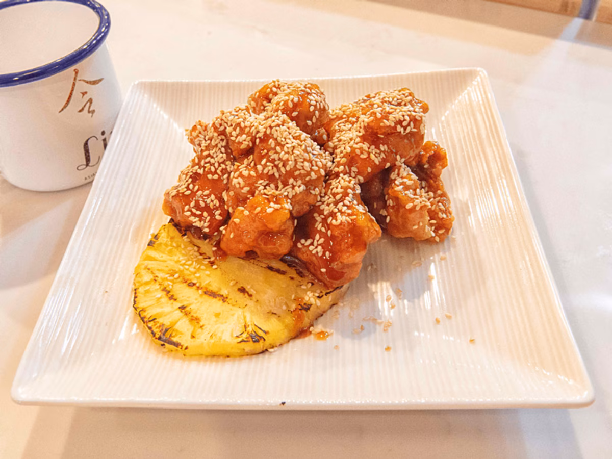Glazed sesame bites with grilled pineapple on a white plate.