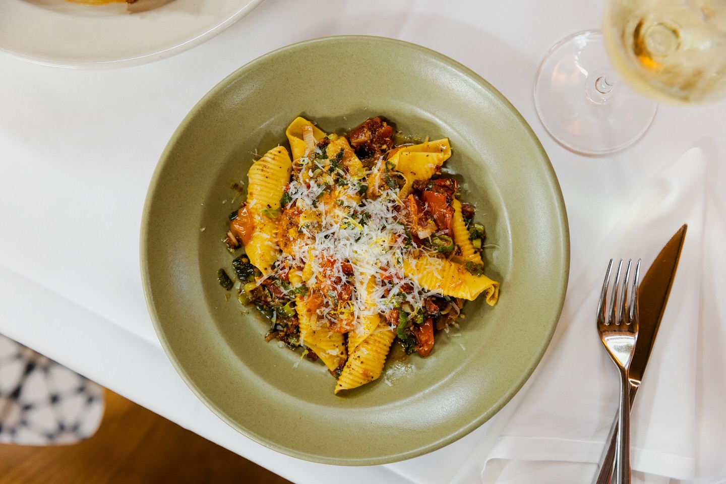 Large shell pasta with chunky sauce and grated cheese in a green bowl.
