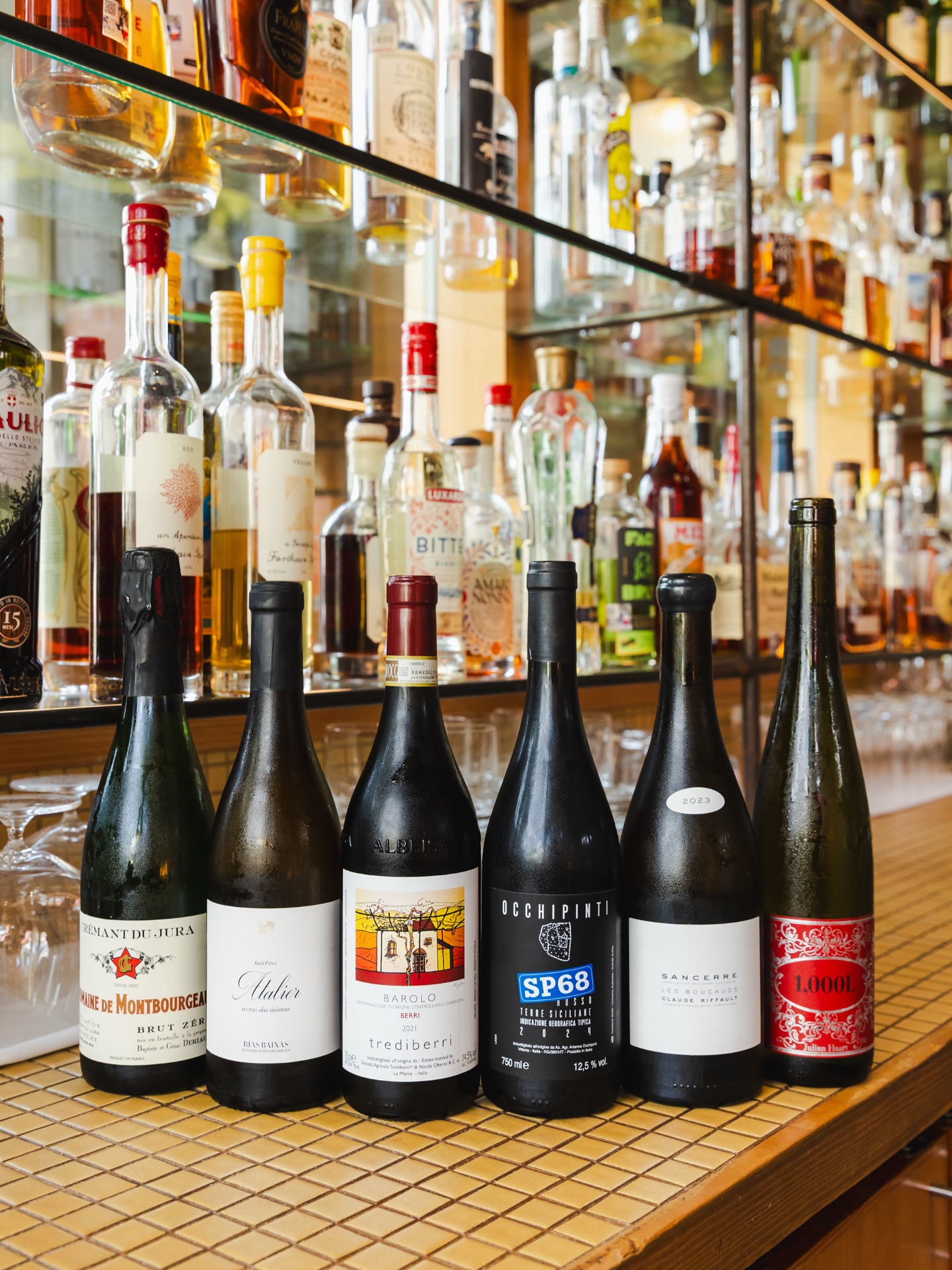 Bottles of wine, spirits, and other liquor on a bar shelf.