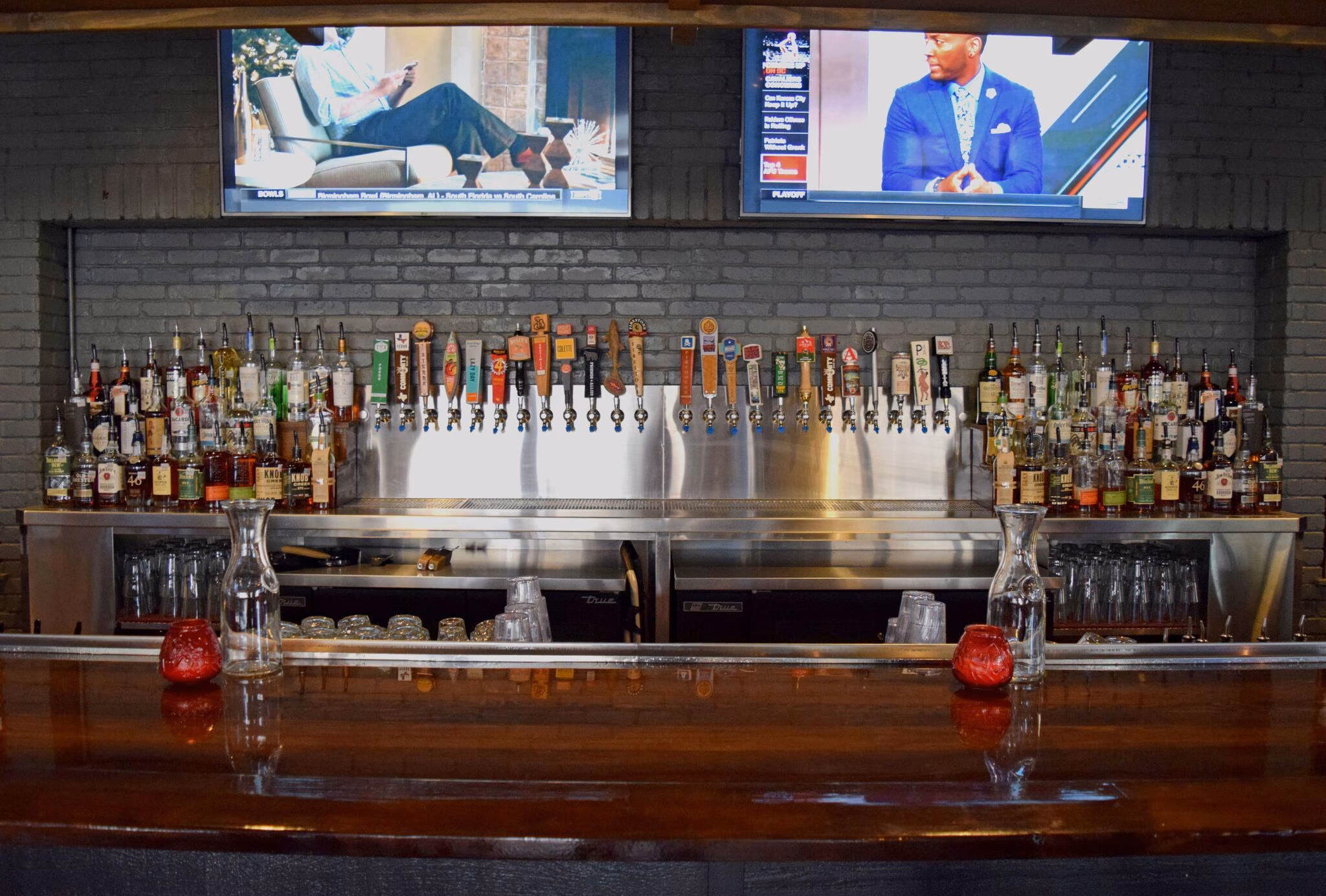 Bar with numerous beer taps, liquor bottles, and two televisions.