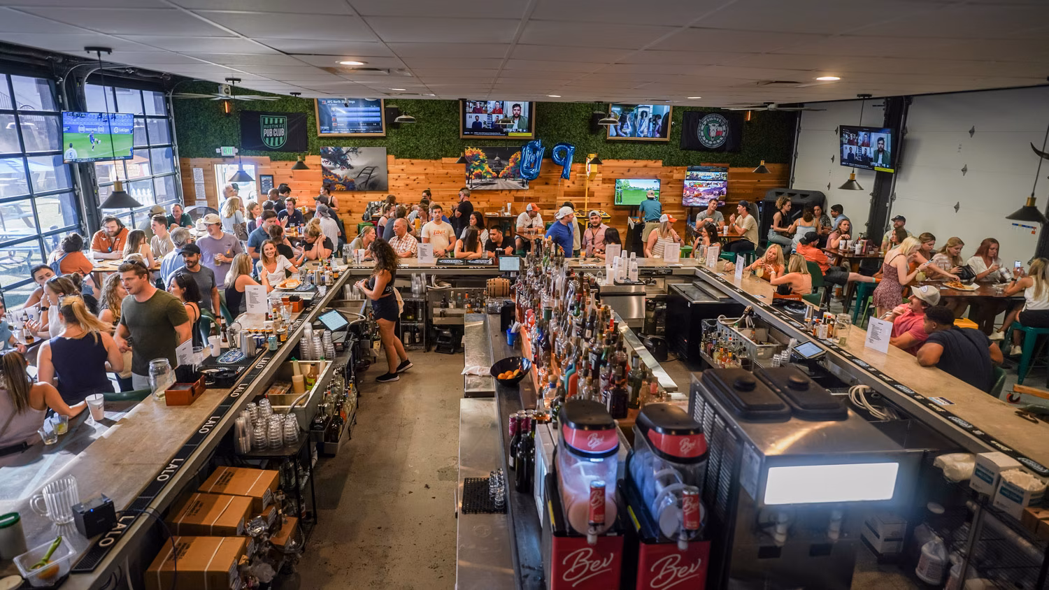 Busy sports bar interior with many patrons and multiple televisions.