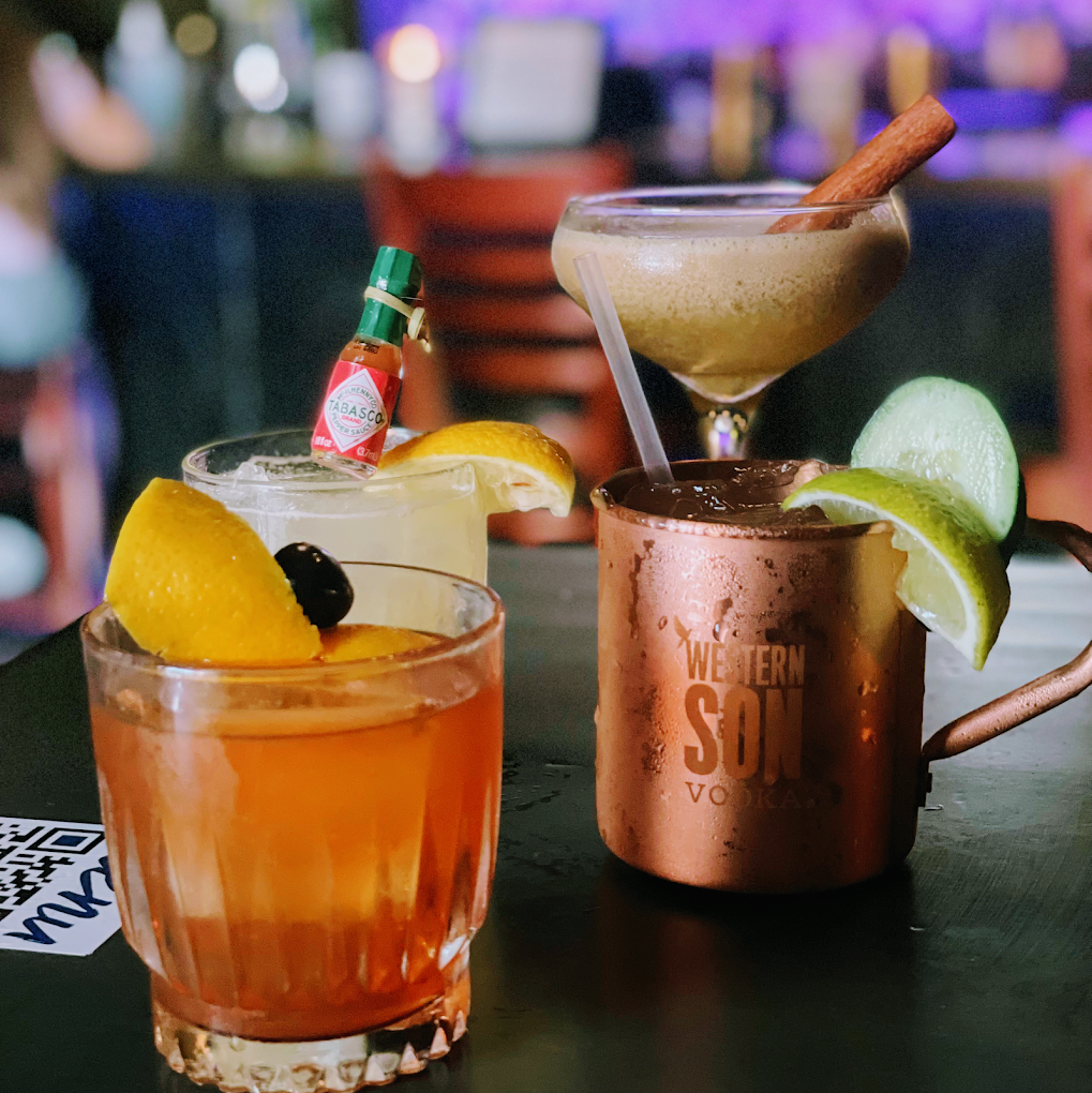 Four diverse cocktails on a bar, with various garnishes.
