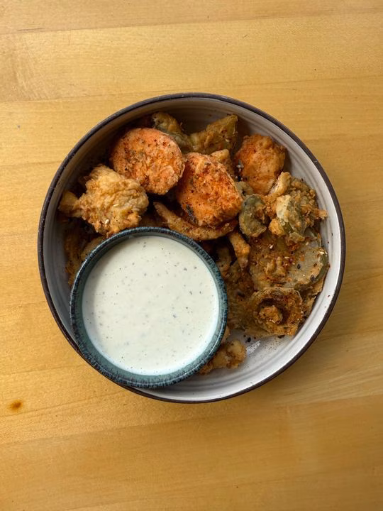 Fried sweet potatoes and pickles with white dipping sauce in a bowl.