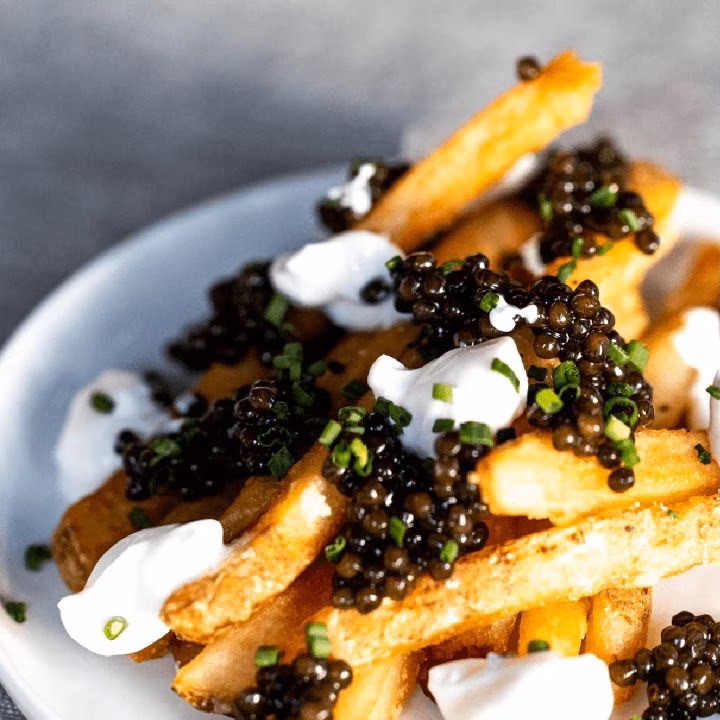 Golden french fries with black caviar, white cream, and chives.