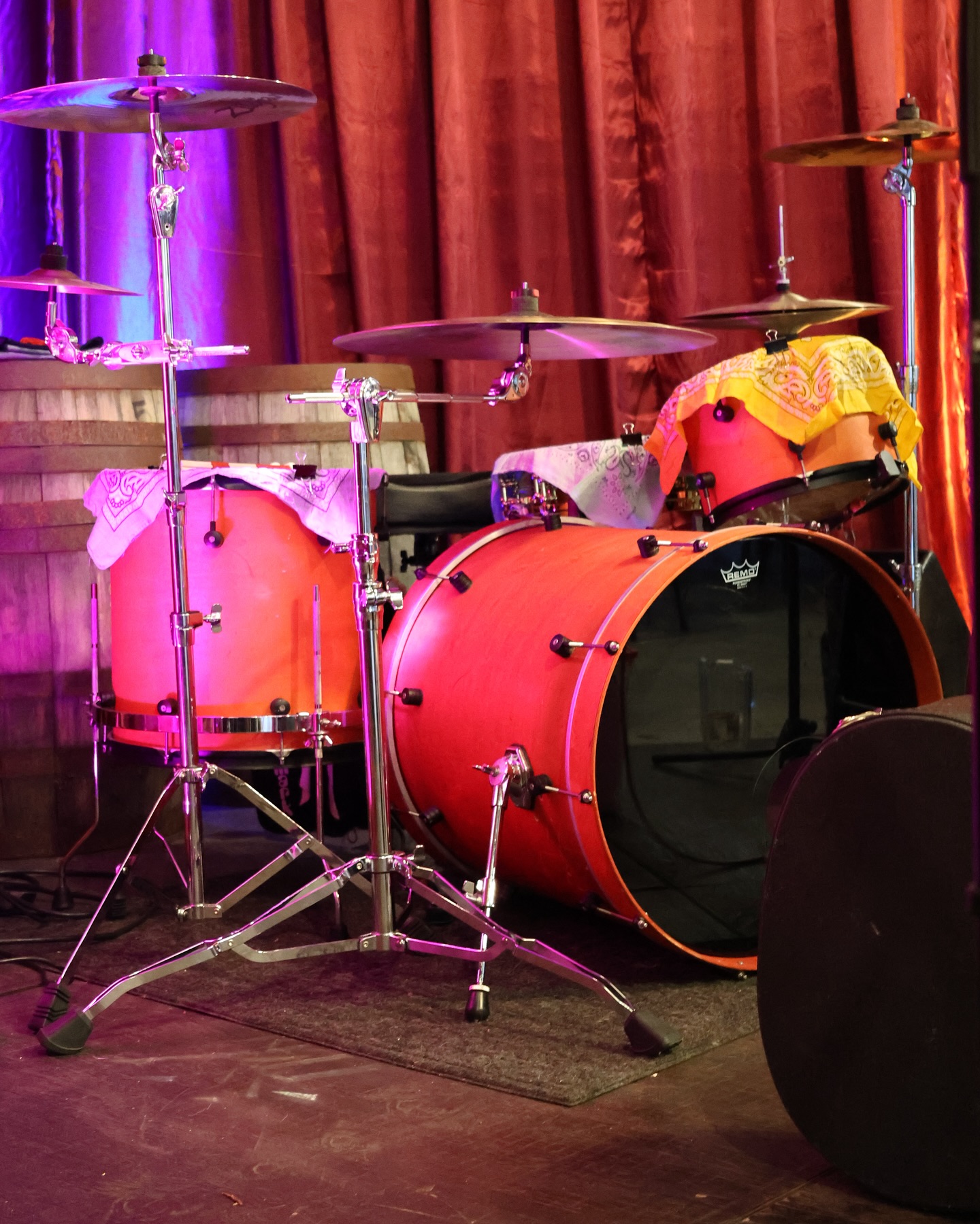 Orange drum kit with cymbals on stage with red and purple lights.