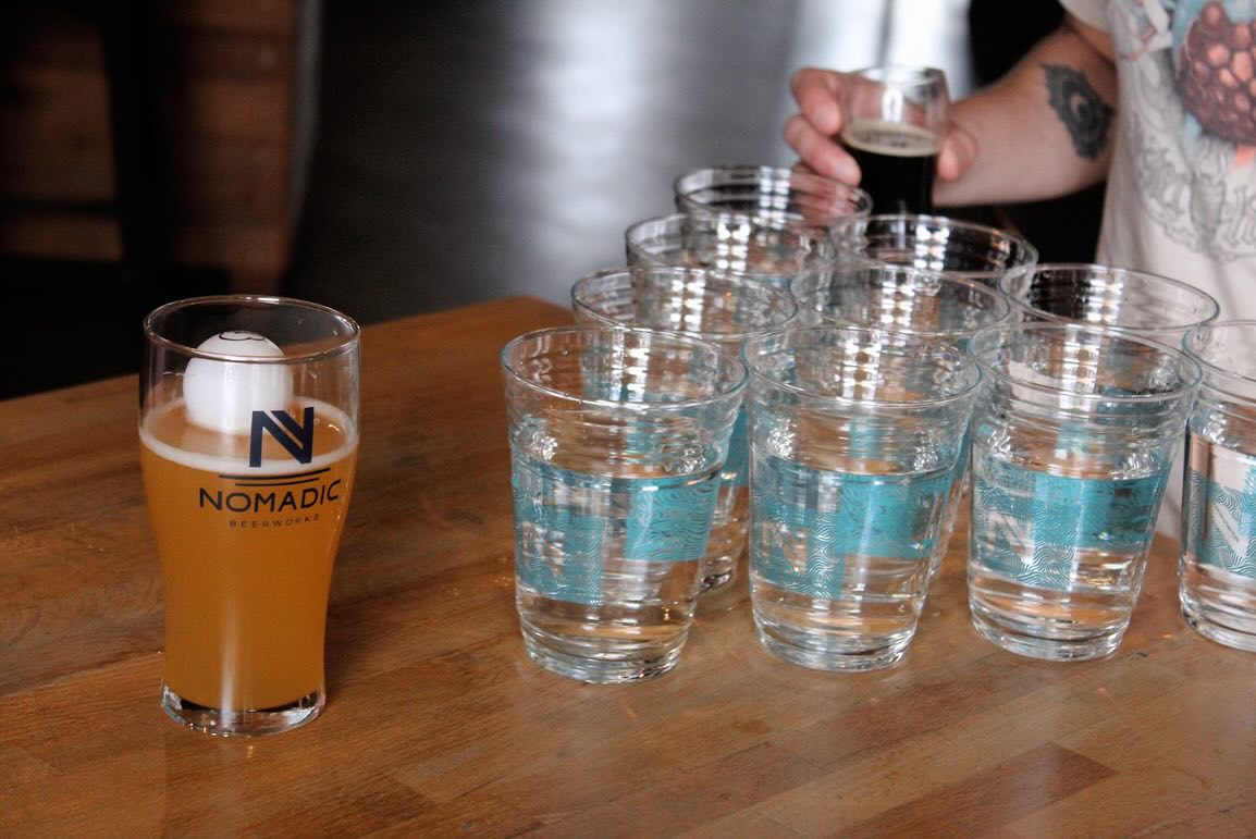 Ping pong ball in beer, person with shot, rows of water glasses.