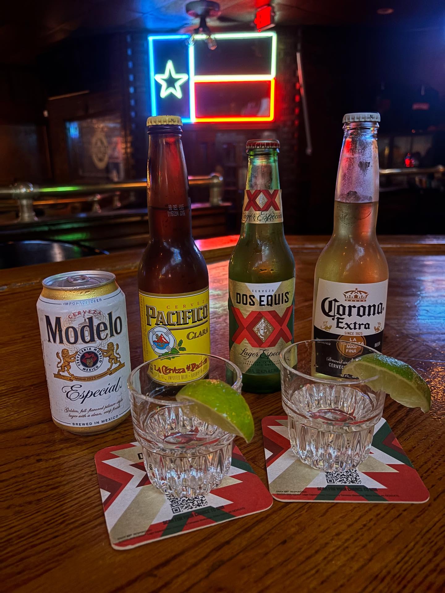 Mexican beers, shot glasses with lime, and Texas flag neon sign.