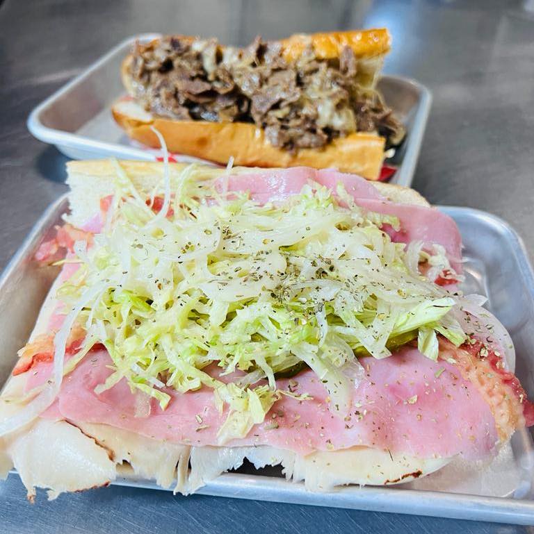 Two submarine sandwiches: a cold cut sub and a cheesesteak.