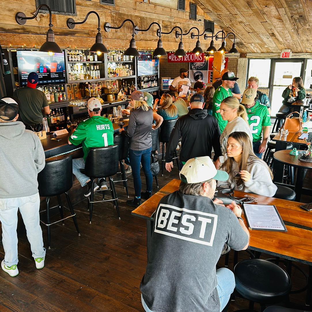 People socializing and drinking in a busy bar with wooden decor.