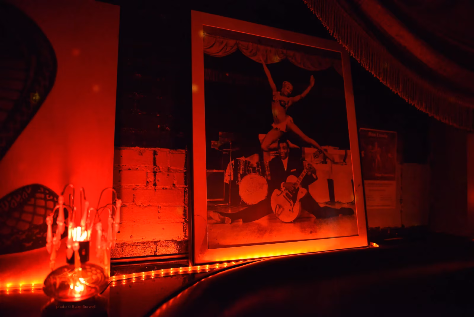 Vintage photo of burlesque dancer and guitarist in a dim red room.