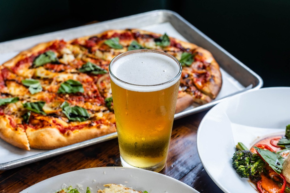 Cold beer and basil pizza on a metal serving tray.