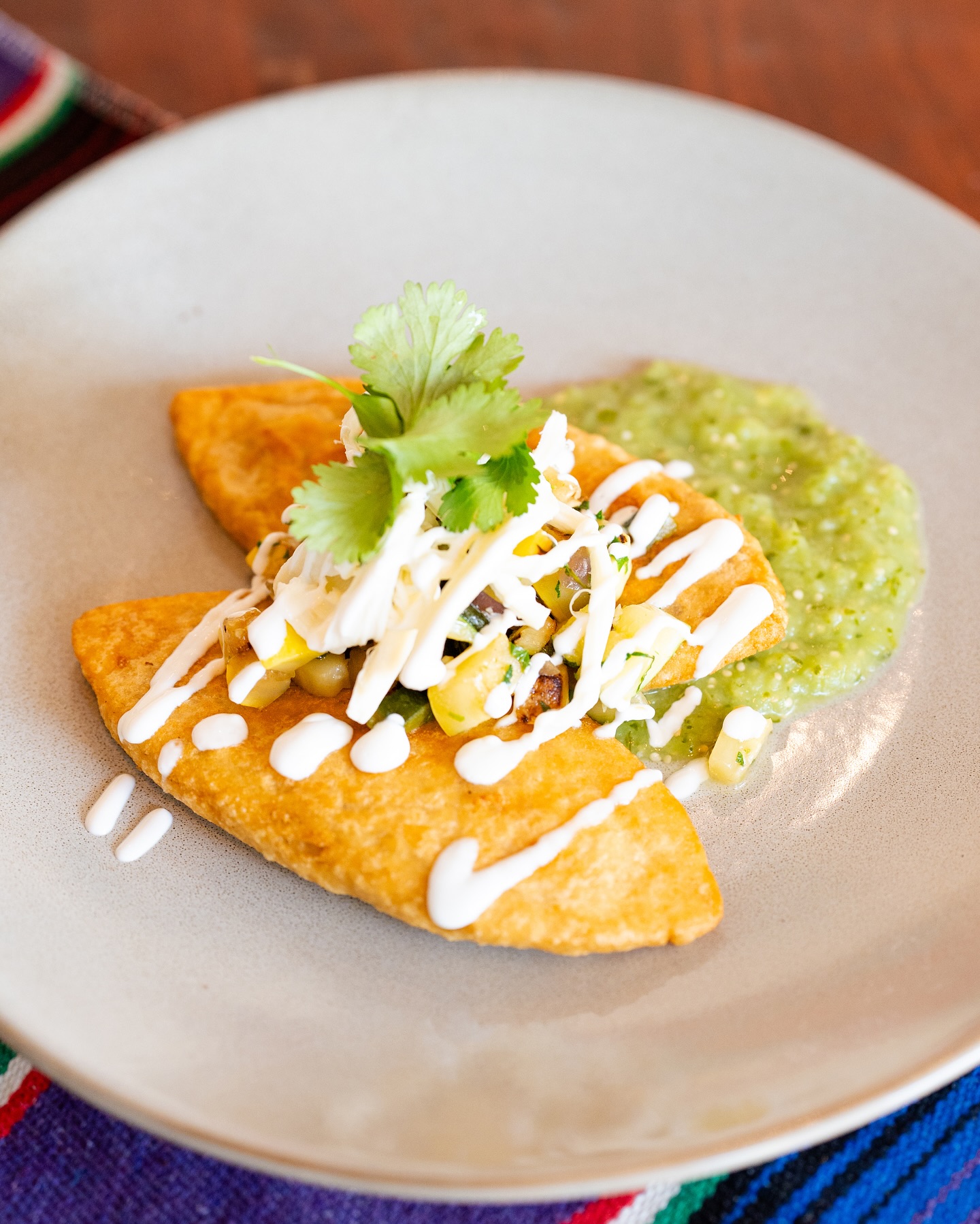 Golden fried empanadas with corn salsa, cheese, cilantro, and green salsa.
