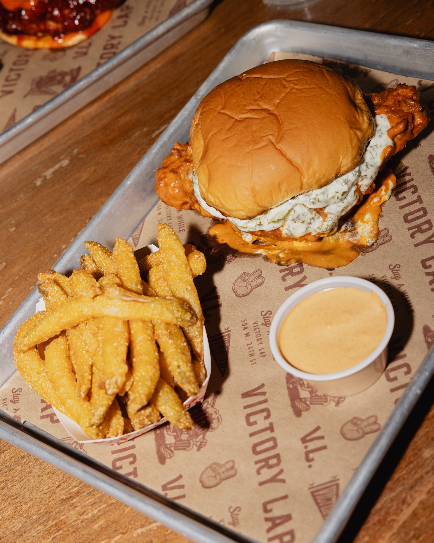 Fried chicken sandwich, fries, and dipping sauce on a branded tray.