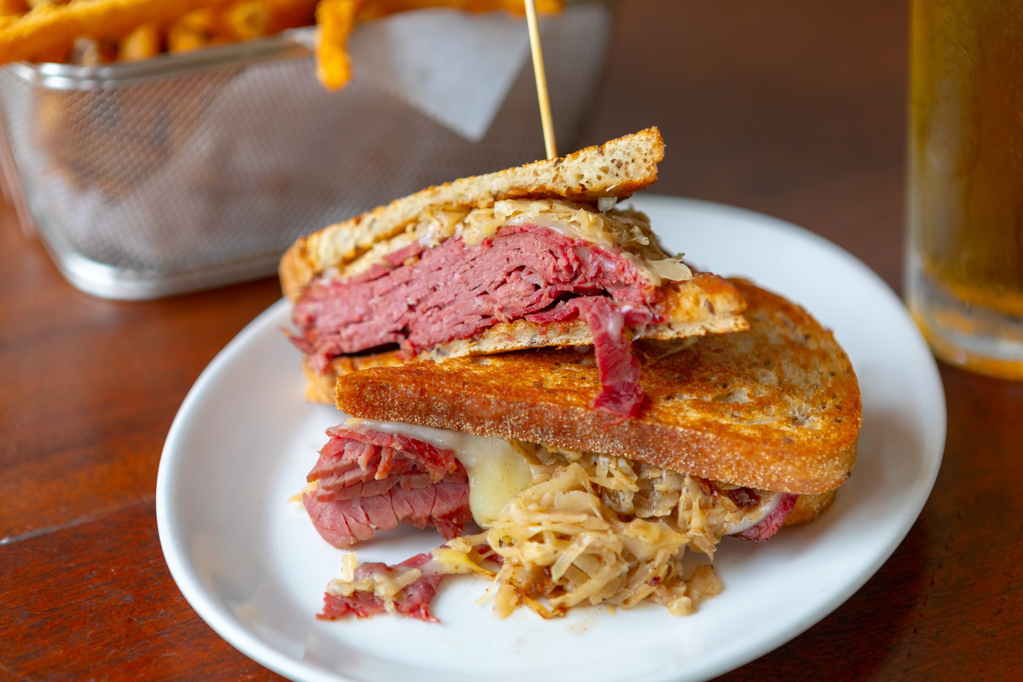 Toasted sandwich with meat, sauerkraut, cheese, fries, and beer.