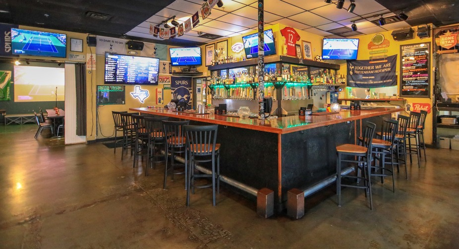 Interior of a Tottenham Hotspur-themed sports bar with many TVs.