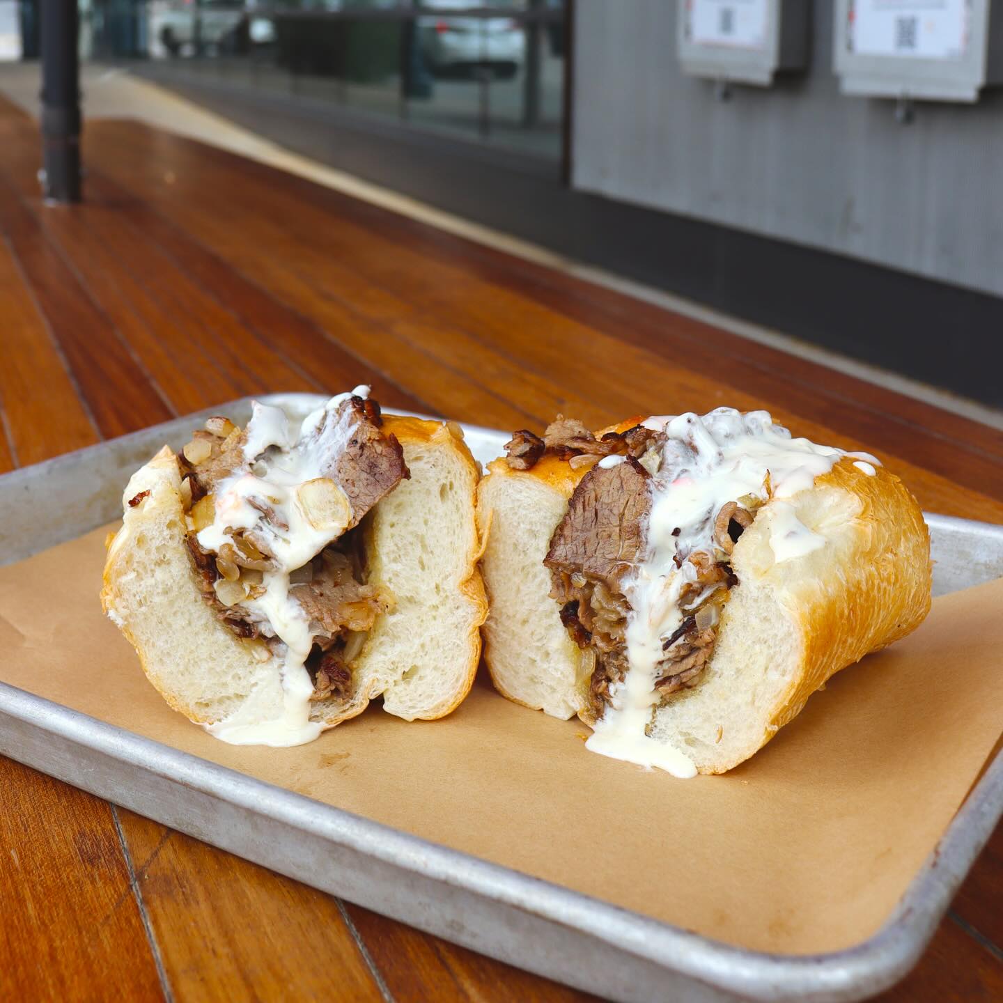 Sandwich cut in half, filled with sliced beef and creamy white sauce.