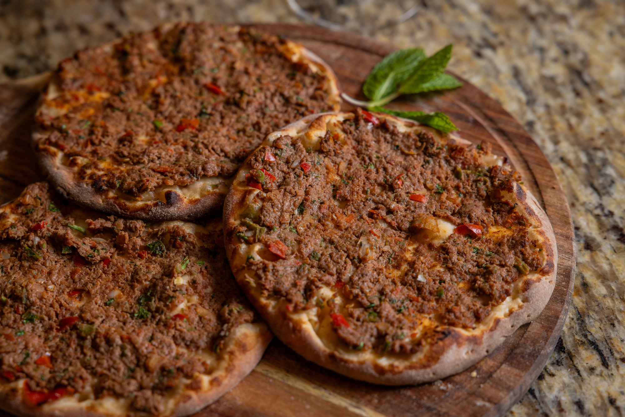 Three round flatbreads topped with minced meat and mint.