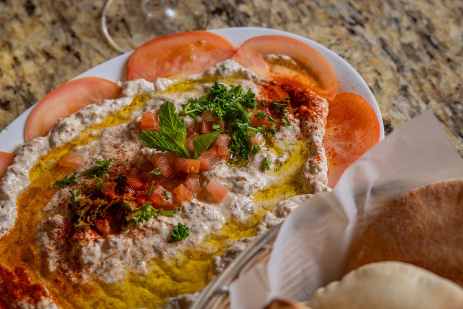 Baba ghanoush topped with olive oil, herbs, tomato, served with pita.